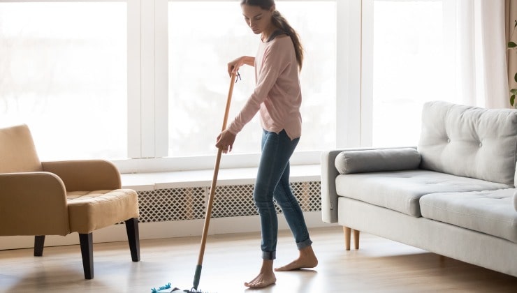 La mujer joven limpia el piso