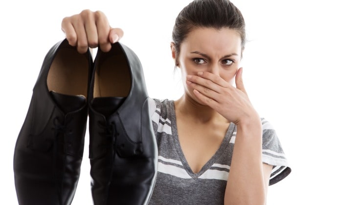 Mujer con zapatos malolientes en la mano