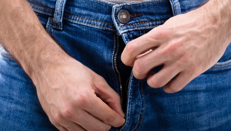 El hombre desliza la cremallera de los jeans azules